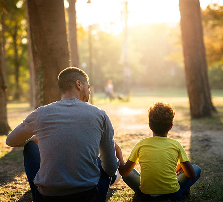 father-daughter-sitting-grass-park-enjoying-sunset-together